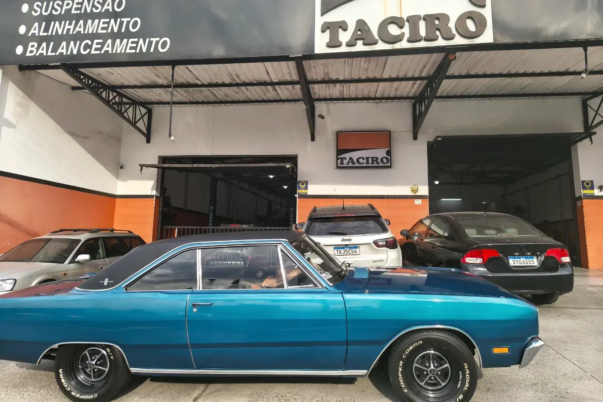 Dodge azul clássico estacionado na frente da Taciro, embaixo da placa de suspensão, alinhamento e balanceamento