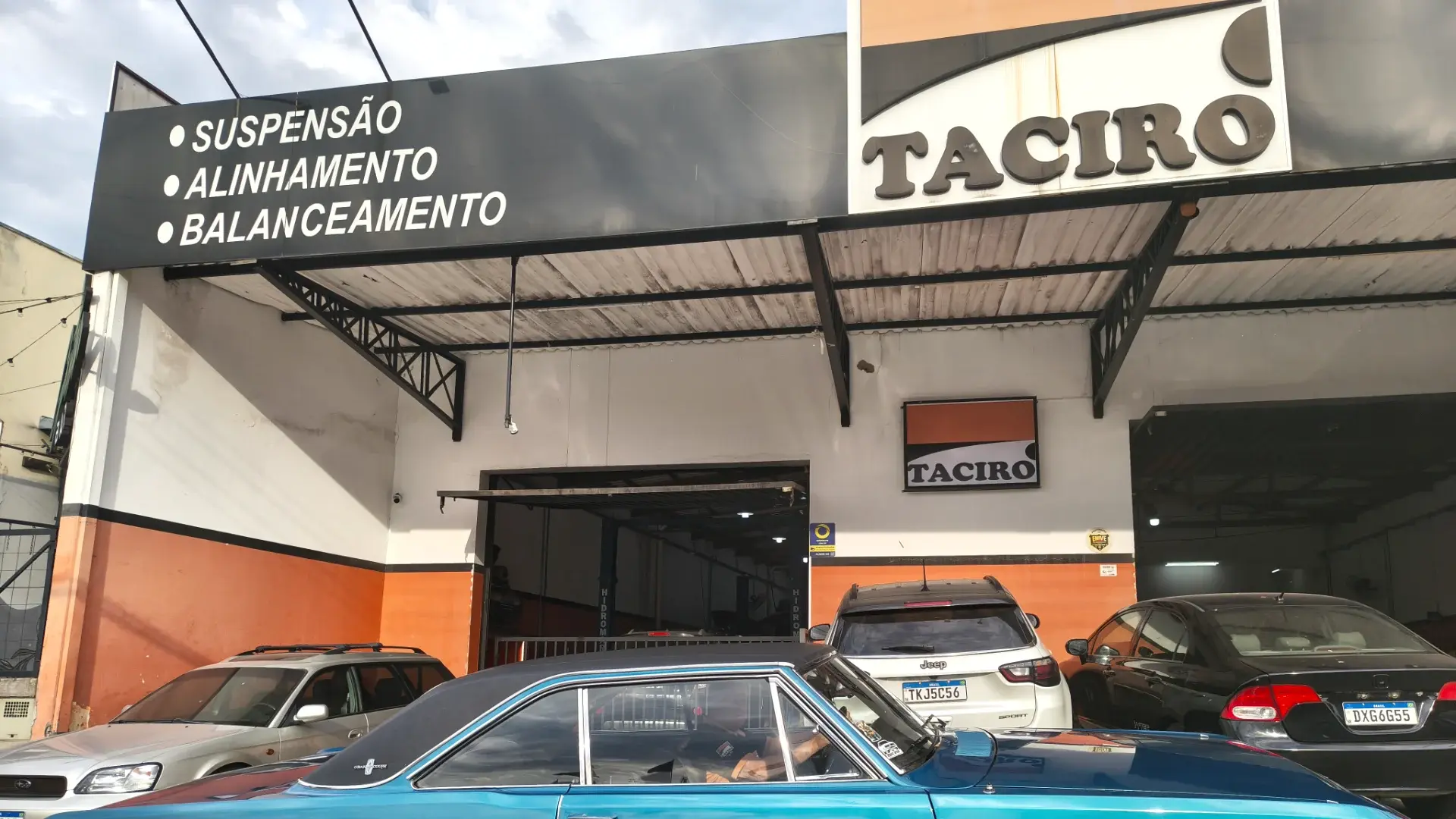 Placa da fachada da Taciro com suspensão, alinhamento e balanceamento escritos, ao lado do letreiro da oficina